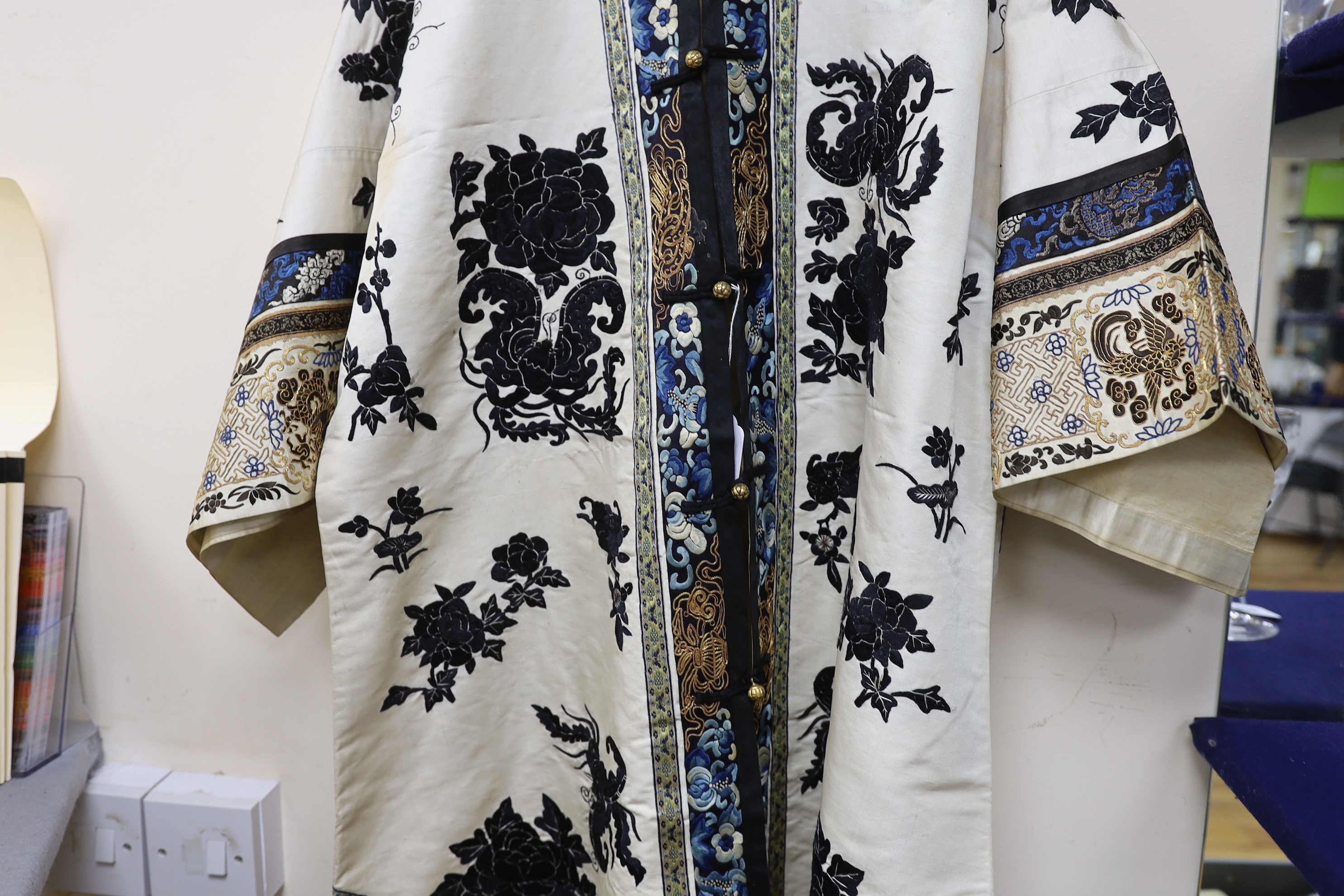 A late 19th/early 20th century Chinese embroidered cream silk robe with black symbolic embroidered all over motifs